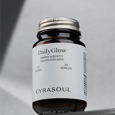 Cyrasoul DailyGlow enerji ve güzellik takviyesinin gümüş kapaklı amber renkli şişesinin stüdyo çekimi. Ürünün modern ve minimalist tasarımı vurgulanıyor.